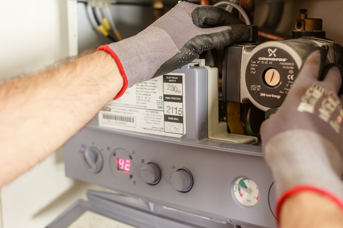 An engineer's gloved hands servicing a boiler
